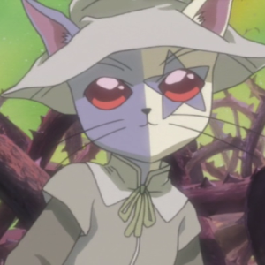 "Macha is an anthropomorphic cat wearing a pointed witch hat and human clothes. Her fur is white and purple, and her left eye has a star shape pattern of purple fur around it."